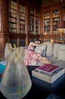 Woman sitting at a table in a luxurious wood-paneled library.