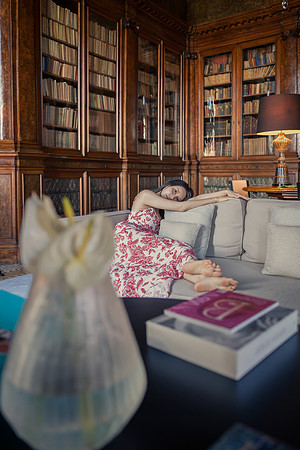 Woman sitting at a table in a luxurious wood-paneled library.