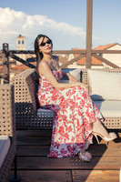Woman in a floral dress sitting on an outdoor lounge chair on a rooftop.
