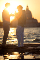 A couple standing by the water during a sunset proposal