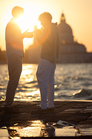 A couple standing by the water during a sunset proposal