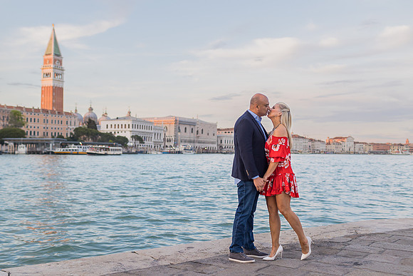 Couple walking by the Venetian waterfront, enjoying a scenic view.