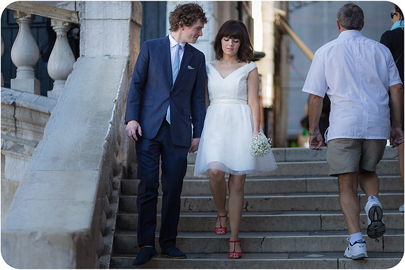 Bride and groom walking hand in hand on a Venetian street.