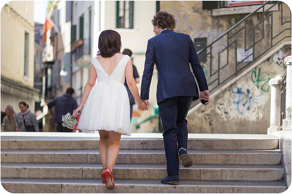 Bride and groom walking up a flight of stairs in Venice.