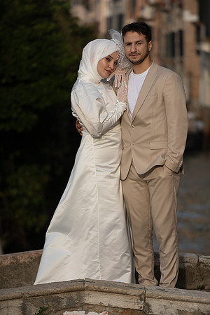 Smiling couple posing on a historic bridge in Venice.