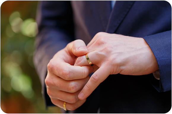 Groom's hands adjusting his wedding ring after the ceremony.