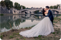 Bride and groom kissing near the Colosseum in Rome during their honeymoon photoshoot.