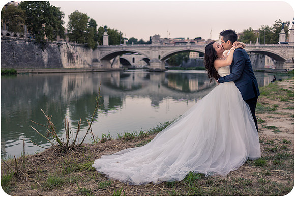 Bride and groom kissing near the Colosseum in Rome during their honeymoon photoshoot.