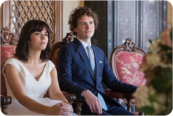Bride and groom sitting in a Venetian wedding hall during the ceremony.
