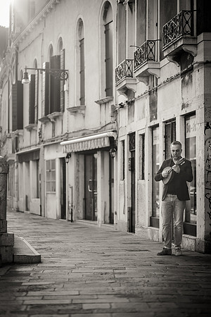 B&W photo of mandolin player Jacob Reuben walking in a narrow Venice street