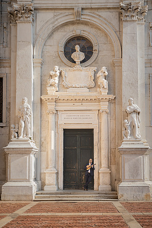 B&W photo of a musician in front of historic architecture