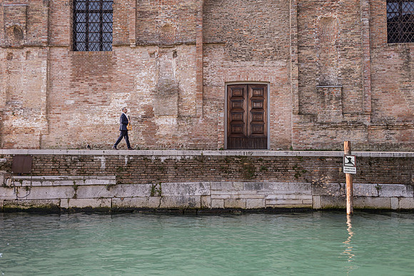 Musician walking on a bridge near a canal
