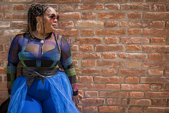 Elegant woman in a blue gown posing by a rustic brick wall in Venice.