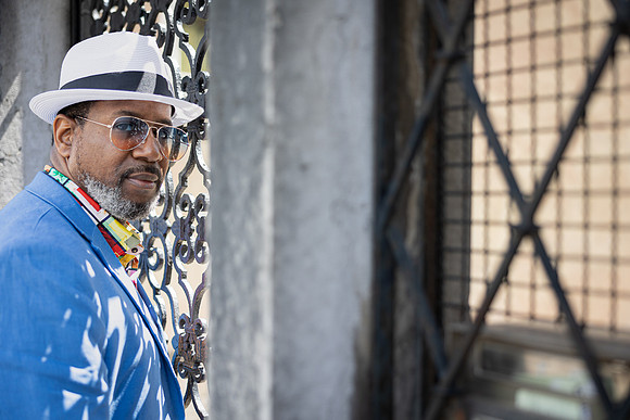 Stylish man in a white hat and blue blazer near a Venice canal.