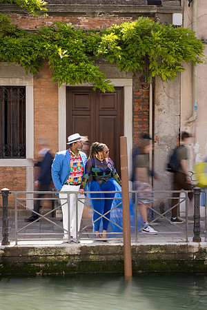 Romantic couple walking along a canal bridge in Venice.