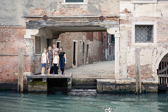 Family walking across a Venetian bridge at sunset during a family vacation