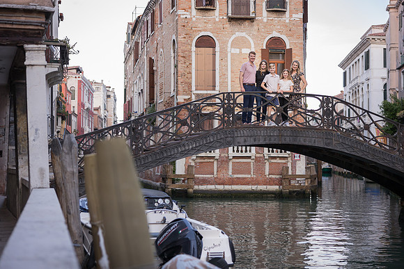 Family crossing a charming Venetian bridge during their family photo session
