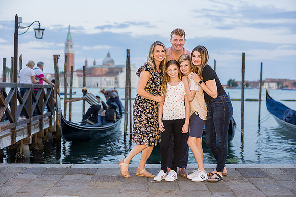 Family gathering near iconic gondolas in Venice at sunset during a family photo session