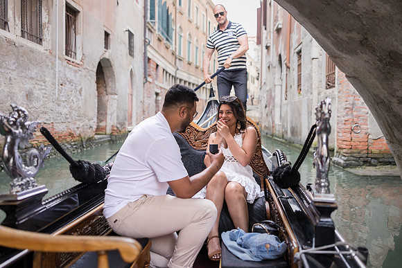 Couple kissing on a gondola ride in a narrow Venice canal.