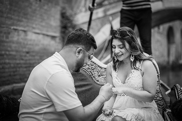 Man kneeling on a gondola, proposing to his partner in Venice.