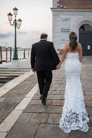Bride and groom walking hand-in-hand toward the waterfront - Anniversary sunrise photoshoot in Venice.