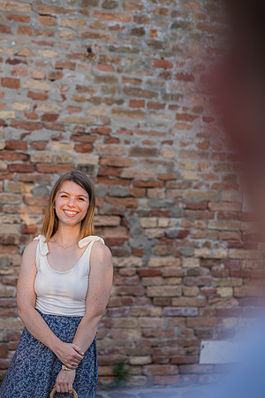Woman in summer dress leaning against a Venetian brick wall at sunset.