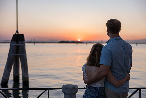 Man looking over the Venetian water at sunset.