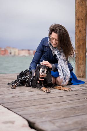 Woman sitting with her dog on Venice dock.