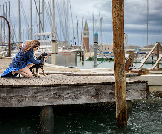Woman and dog on Venice pier with boats.