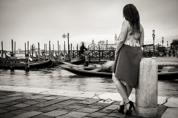 Woman admiring gondolas in Venice with her dog.