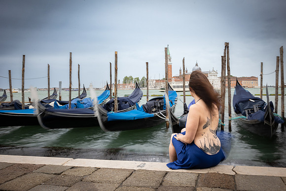Woman sitting by the waters in Venice with her dog.