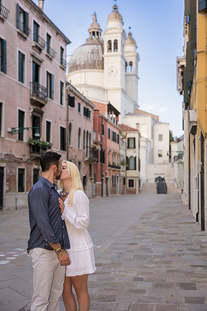 Couple standing near railings in Dorsoduro looking at Venice skyline.