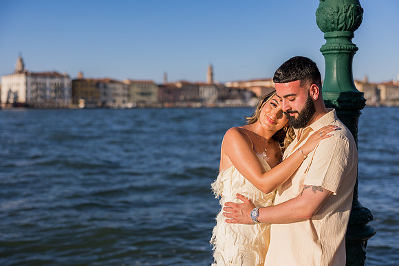 Engaged couple sharing a loving embrace at sunset in Venice.