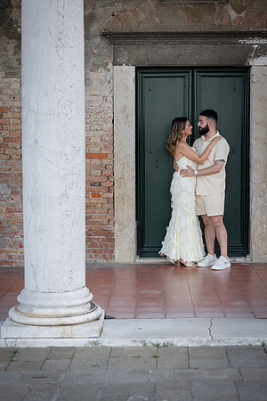 Engaged couple standing under elegant Venetian columns.