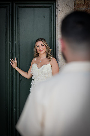 Woman in a white dress standing by a Venetian doorway.