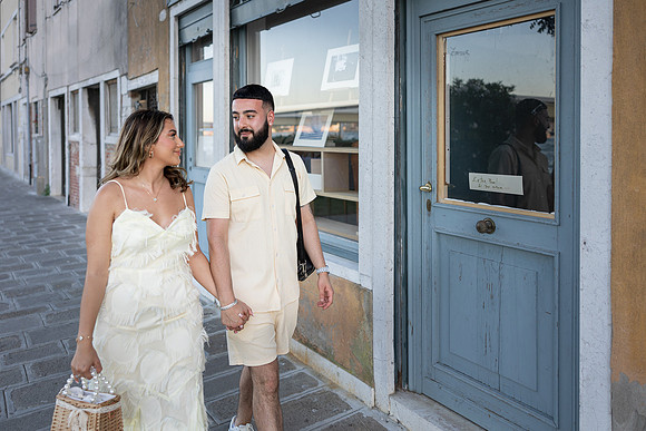 Couple walking hand in hand through a quiet Venetian alley.