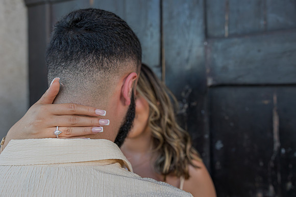 Close-up of a woman’s hand resting on her fiancé’s shoulder.