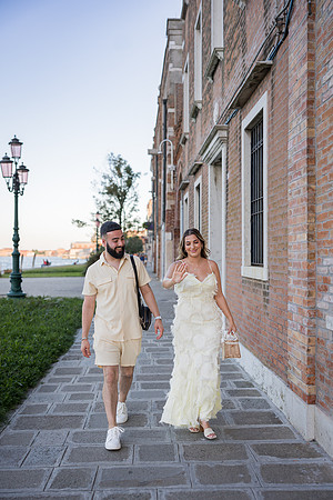 Engaged couple walking along a historic pathway in Venice.