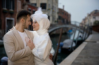 Engaged couple posing romantically with Venetian canals behind them.