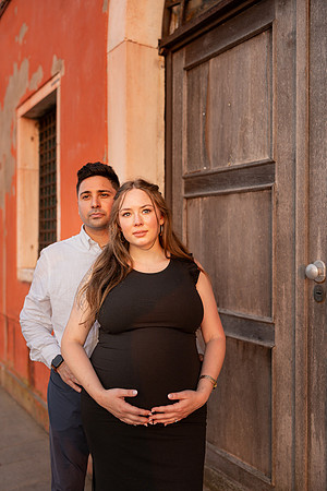 Expecting couple posing by Venetian building