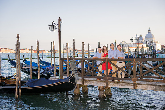 Family portrait on a wooden pier in Venice, with gondolas and landmarks in the background.