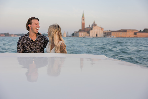 Smiling couple on water taxi with Venice skyline background