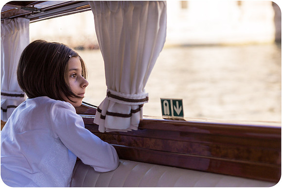 Young girl looking out of the water taxi window in Venice during the wedding day.