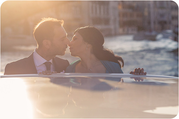 Bride and groom sharing a romantic moment on a water taxi at sunset in Venice.