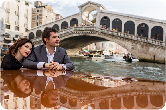 Romantic couple leaning on a boat near the Rialto Bridge in Venice.