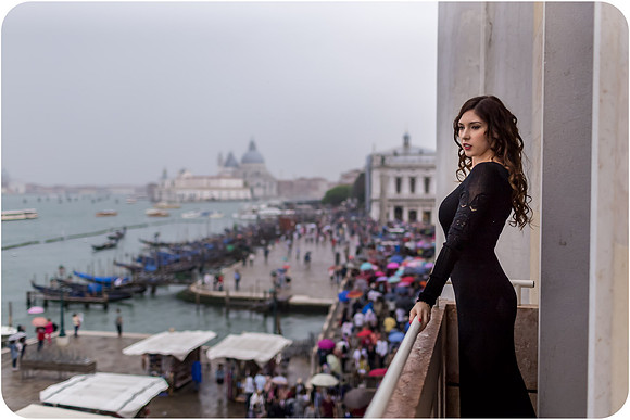 Elegant woman in a black gown standing on the balcony of Hotel Danieli overlooking Venice.