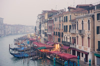 A peaceful view of the Grand Canal at sunrise, with Rialto Bridge in the background.