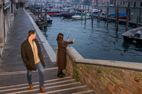 Couple standing by the canal, admiring the water in Venice.
