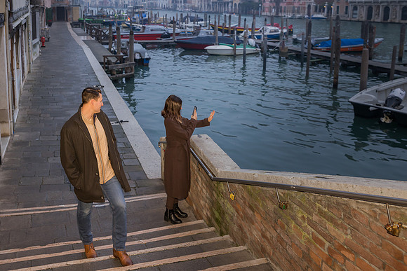 Couple standing by the canal, admiring the water in Venice.