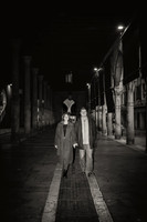 Silhouetted couple walking hand in hand through a Venetian street.